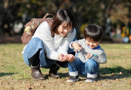 公園で落ち葉を拾いながら笑顔の母と子