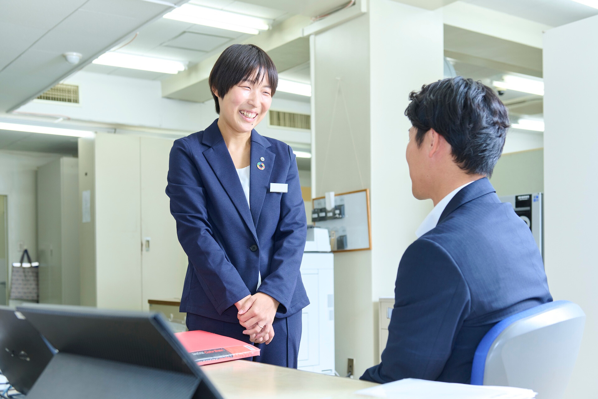 女性社員が男性社員と会話している様子