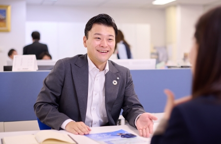 デスクで笑顔で商談をするスーツ姿の男性